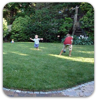 Picture of children playing in green lawn with patio and flowering garden